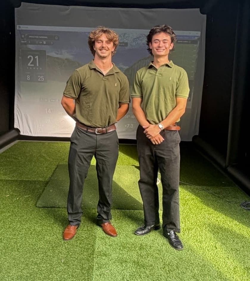 Stone Fowler and Eitan Minyan standing together inside the Eston Mobile Golf enclosure, in front of the impact screen.